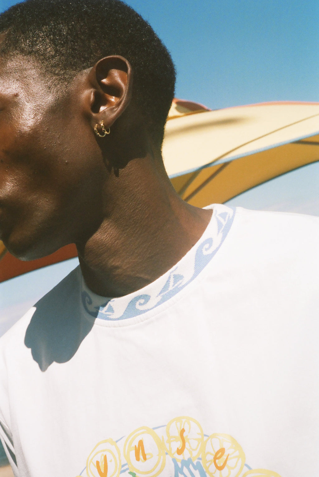 A close-up side profile of a man wearing a white branzino t-shirt.