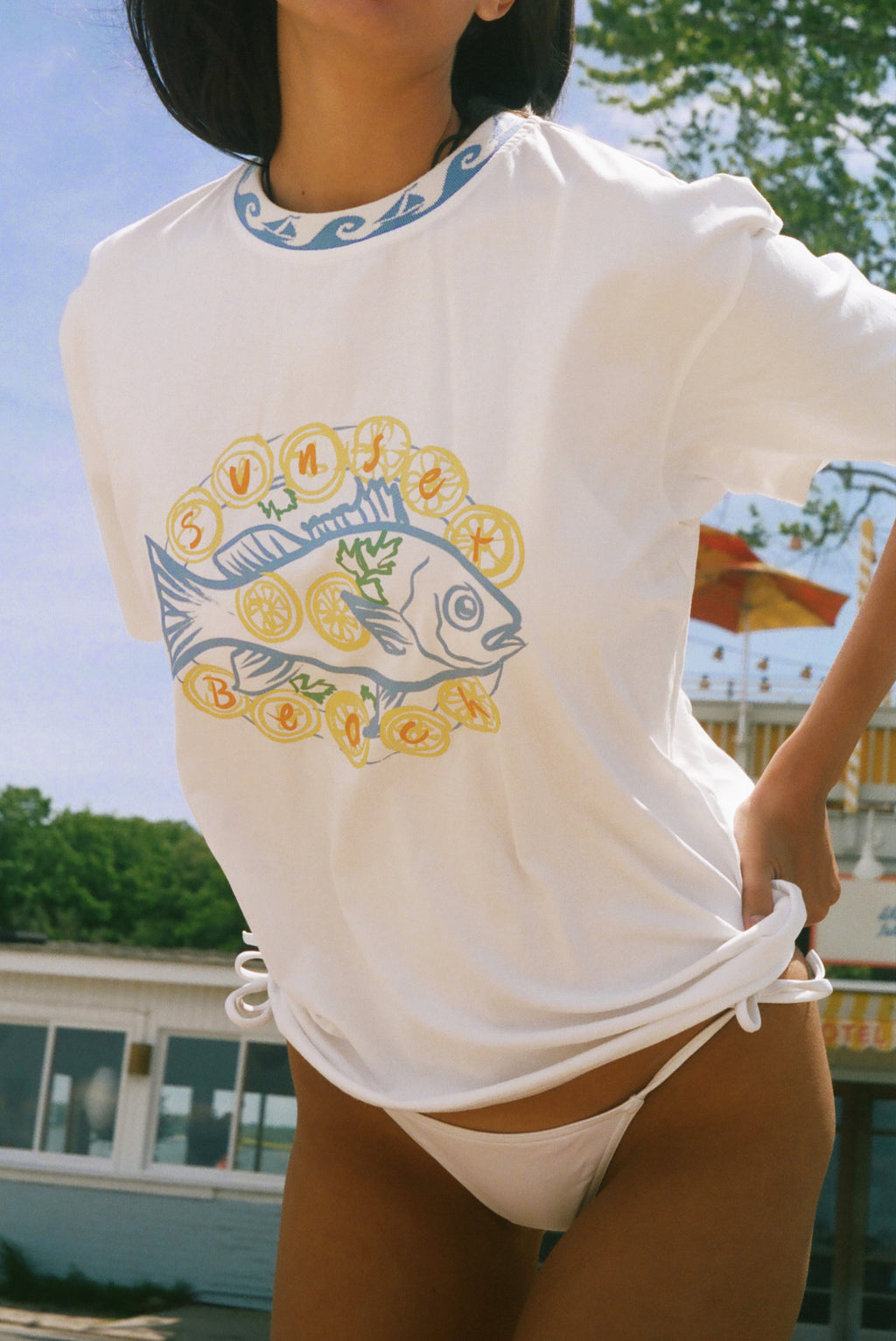 A woman wearing a white short-sleeve t-shirt with a graphic of a blue fish