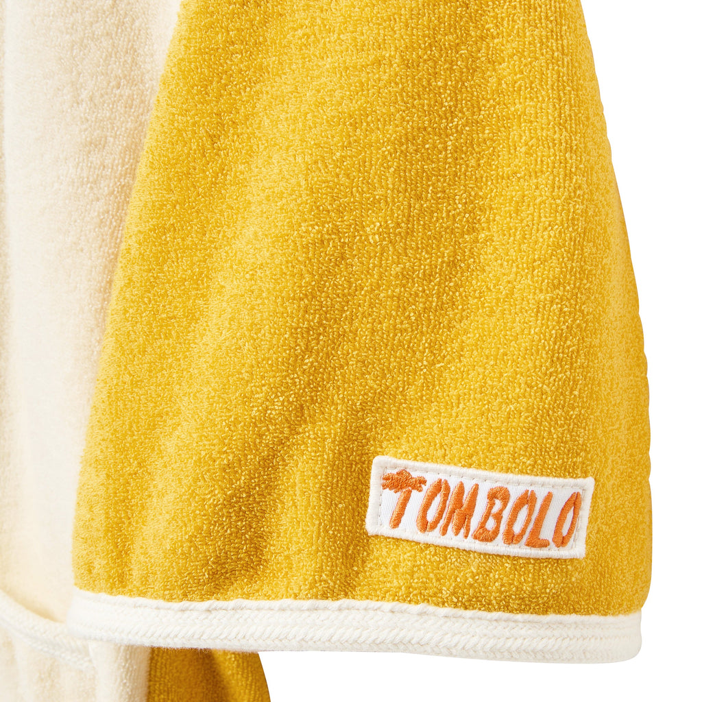 Yellow towel sleeve a white label featuring the brand 'Tombolo' on a white background