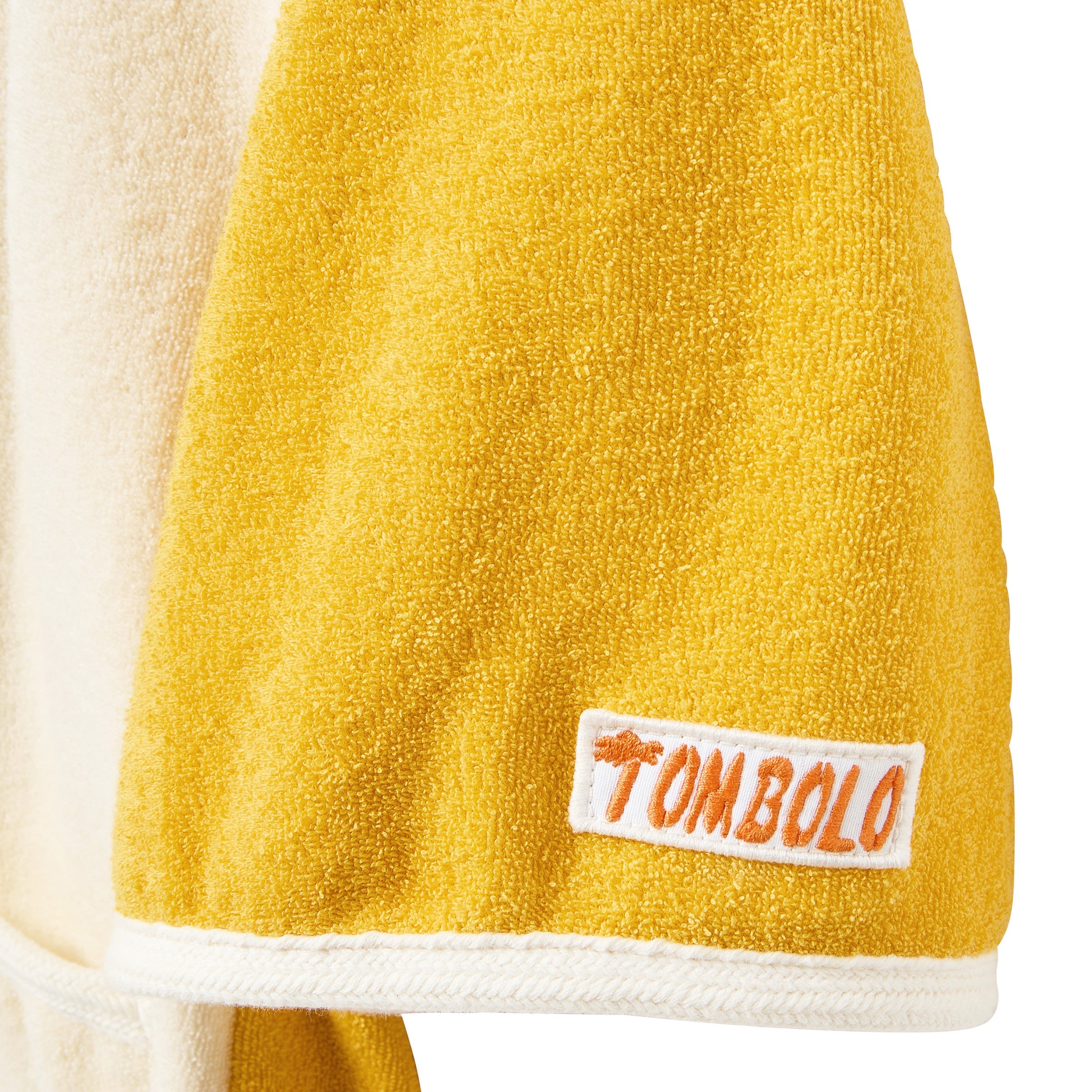 Yellow towel sleeve a white label featuring the brand 'Tombolo' on a white background
